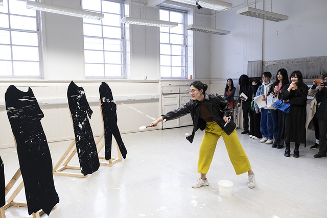 An artist working in a studio while a group observes