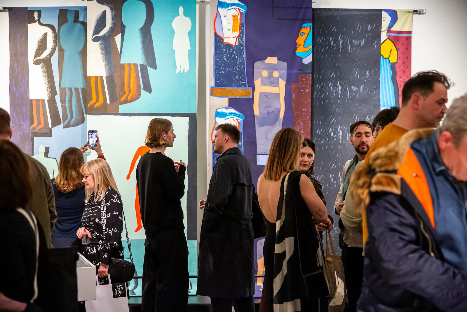 Visitors talking in front of a colourful textile exhibition display