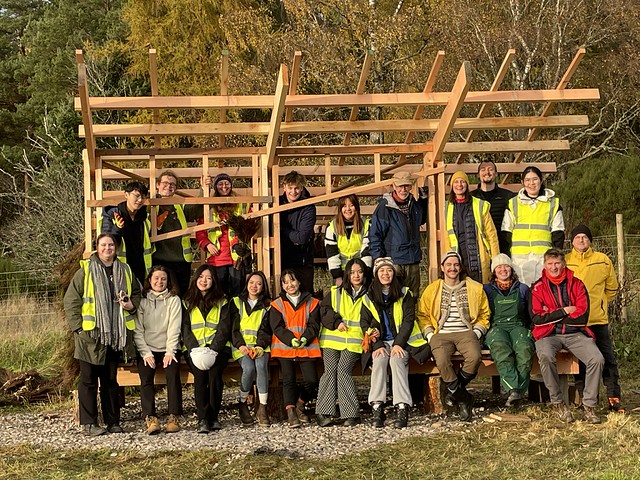 A group collaborating on a wooden structure outdoors