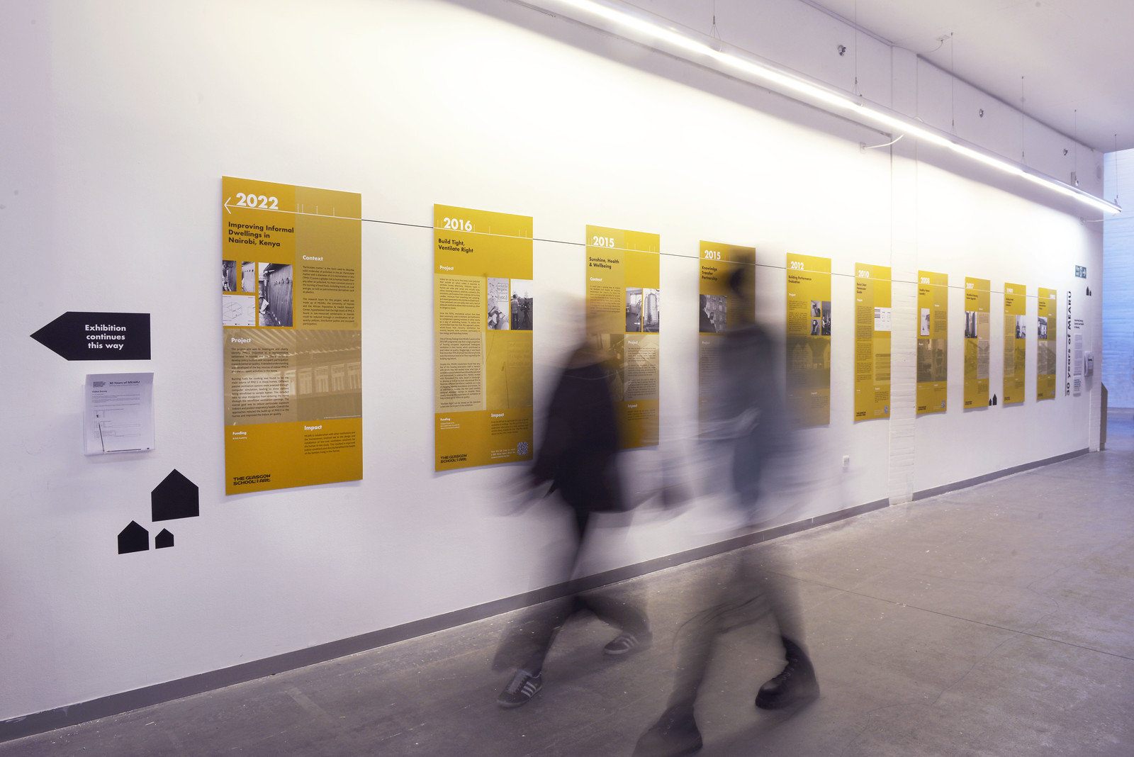 Visitor walking past the 30 Years of MEARU exhibition